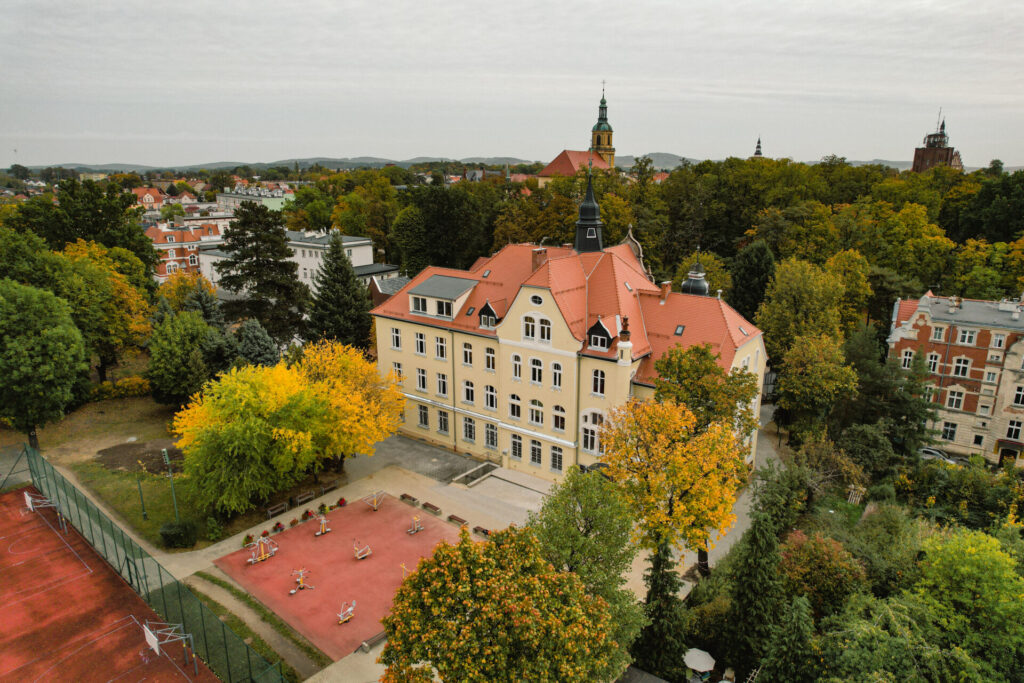 budynek szkoły z tyłu, ujęcie z oddali, lekko z prawej strony